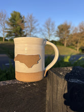 Load image into Gallery viewer, Handmade North Carolina Mug by Acorn Pottery on a fence post